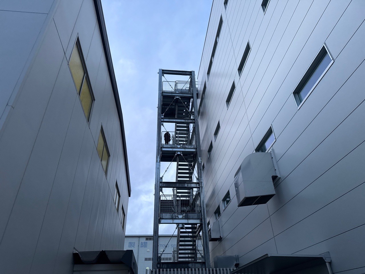 埼玉県久喜市の工場。5〜6層の建物間にある高層屋外階段の全景